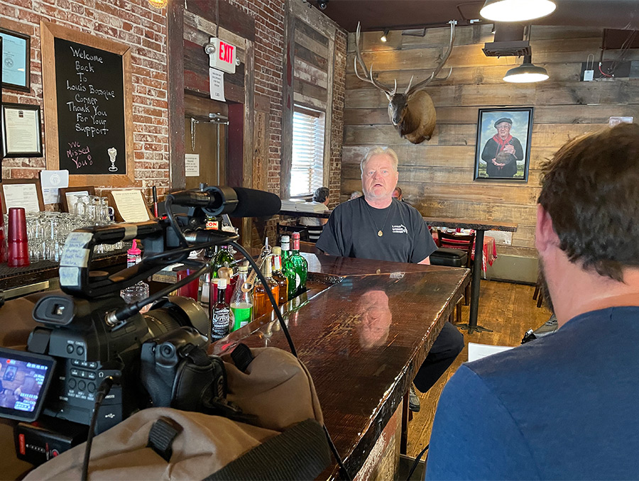 A documentarian interviewing an employee at Louis' Basque Corner on camera.
