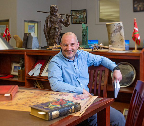 Inaki Arrieta Baro sitting at a table inside the Basque Library with books and posters spread out on the table in front of him.