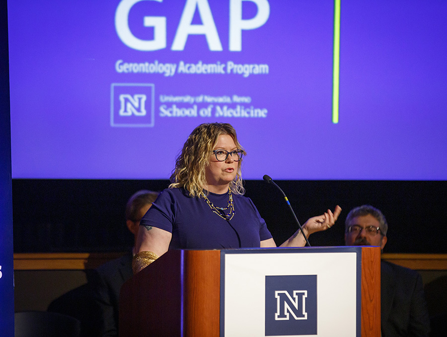 Theresa B Skaar speaking at a podium with the Gerontology Academic Program logo in the background