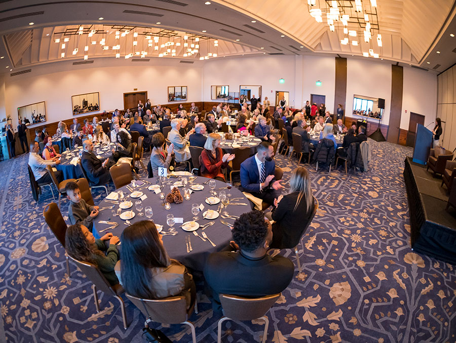 Guests sit around tables in a hotel ballroom for the first annual Sports Management Summit dinner.