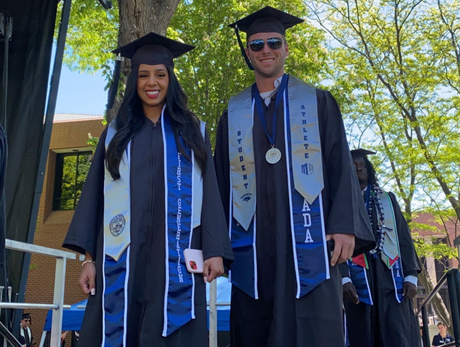 Two College of Business students pose in regalia before entering the stage.