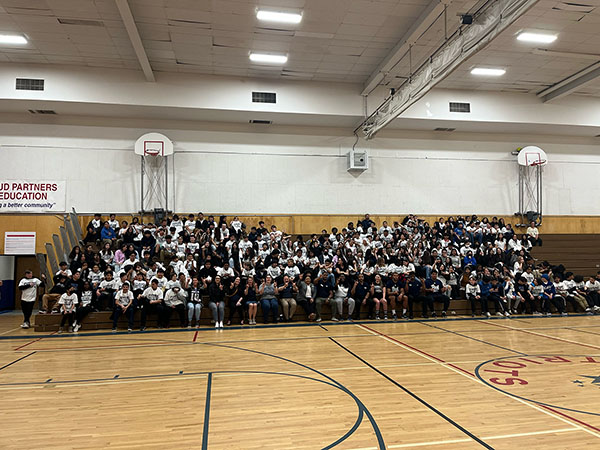 200 students sit in bleachers in a gym.