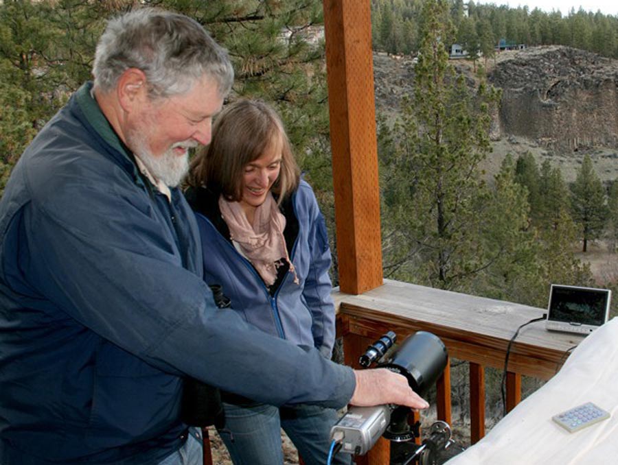 A man and woman set up a camera toward a cliff face.
