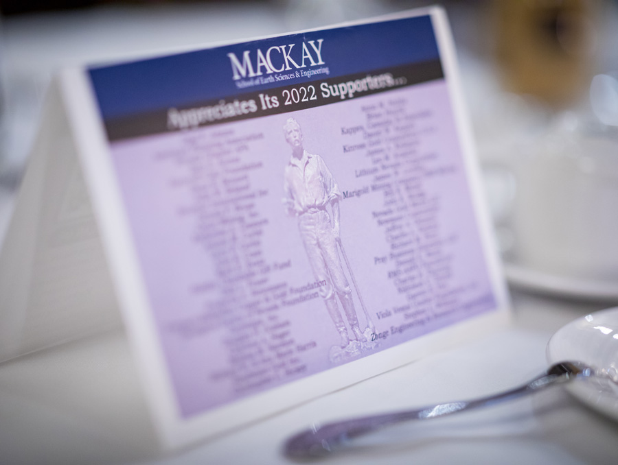 A table tent listing sponsors of the Mackay School. There is a fork and plate in the foreground.