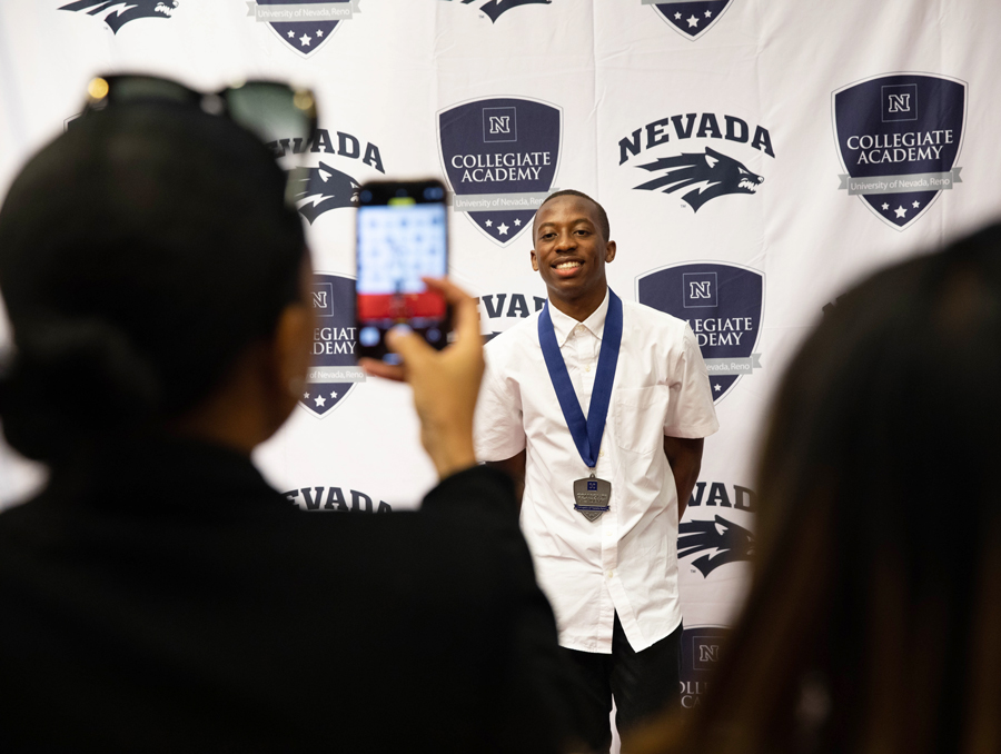 Student gets photo taken against a collegiate Academy backdrop