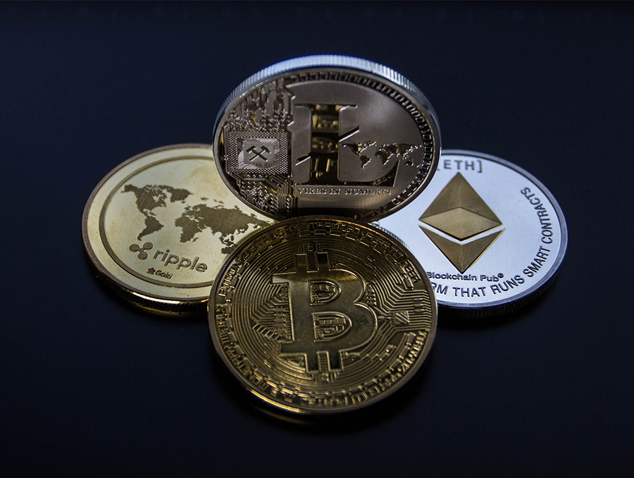 Four gold coins, representing four different cryptocurrencies, arranged in a diamond shape on a black background