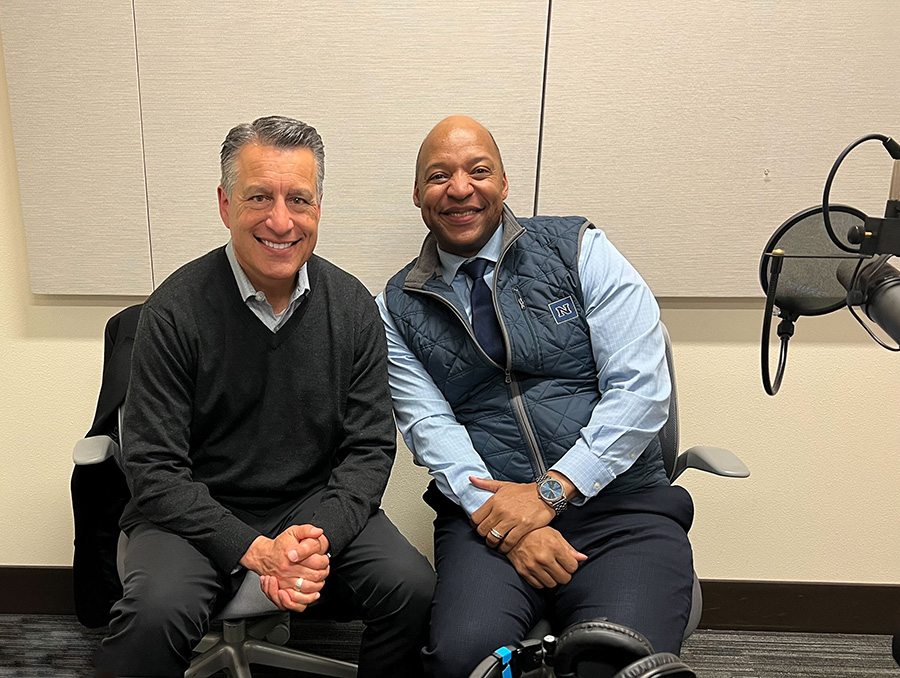 President Sandoval sits to the left of Dean Erick Jones in a podcast recording room with three mics on the table in front of them.