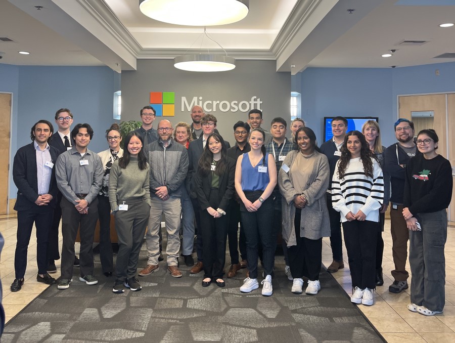 Group of students standing in front of gray wall with Microsoft's logo on it