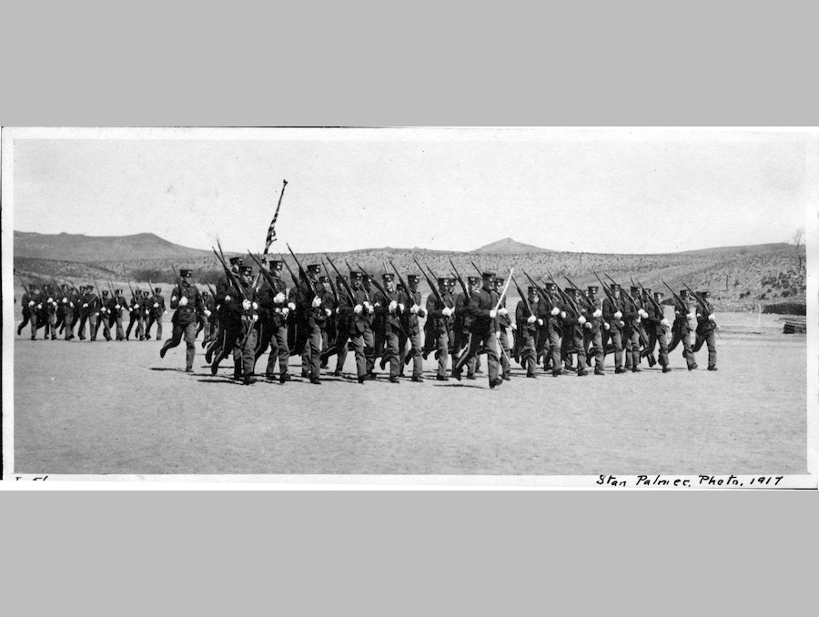 Black and white photo from 1917 of a large group of cadets in uniform marching in formation on Mackay Athletic Field.