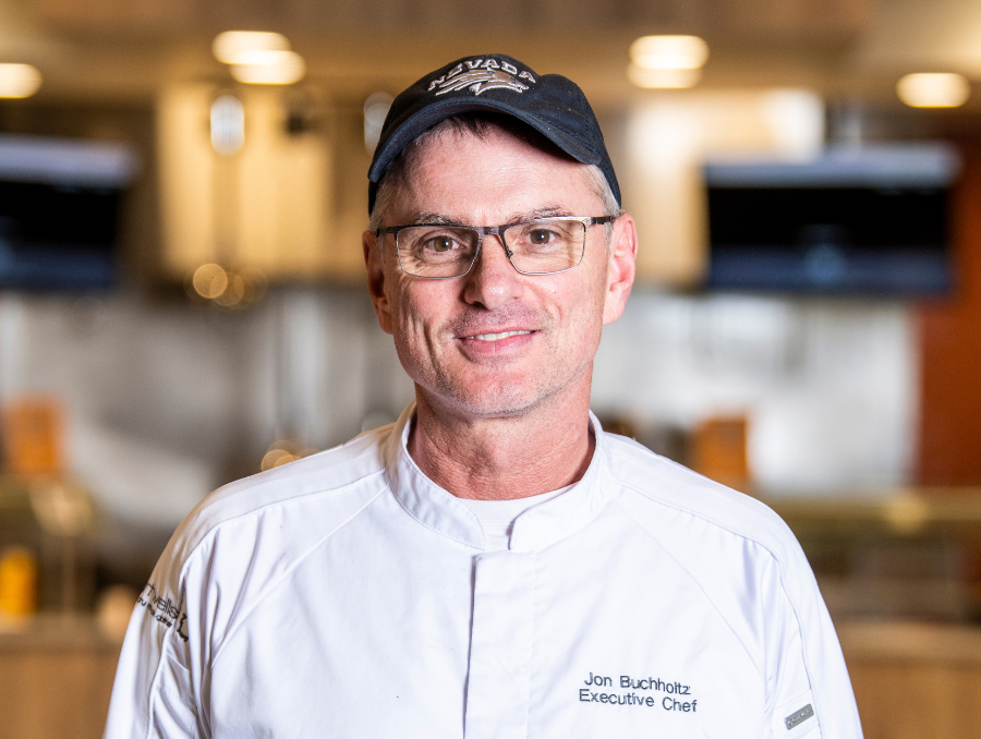 Chef Jon Buchholtz headshot wearing a Nevada baseball cap and a chef jacket, that says Executive Chef.