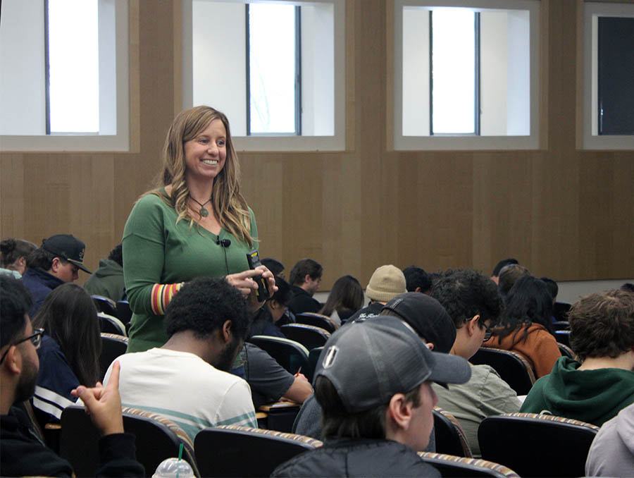 Ann-Marie Vollstedt standing in an auditorium classroom among a group of seated students.