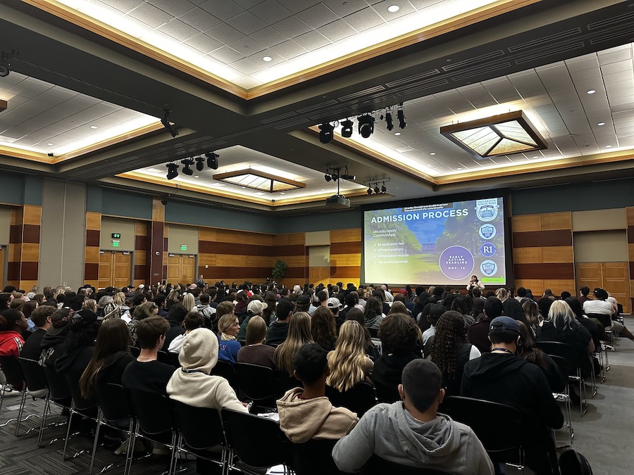 A large auditorium full of high school students in the JCSU ballroom watch a PowerPoint presentation about recruitment.