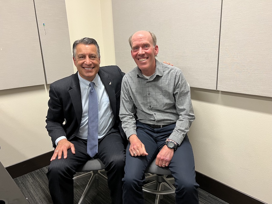 President Brian Sandoval sits next to John Trent in a podcasting studio.