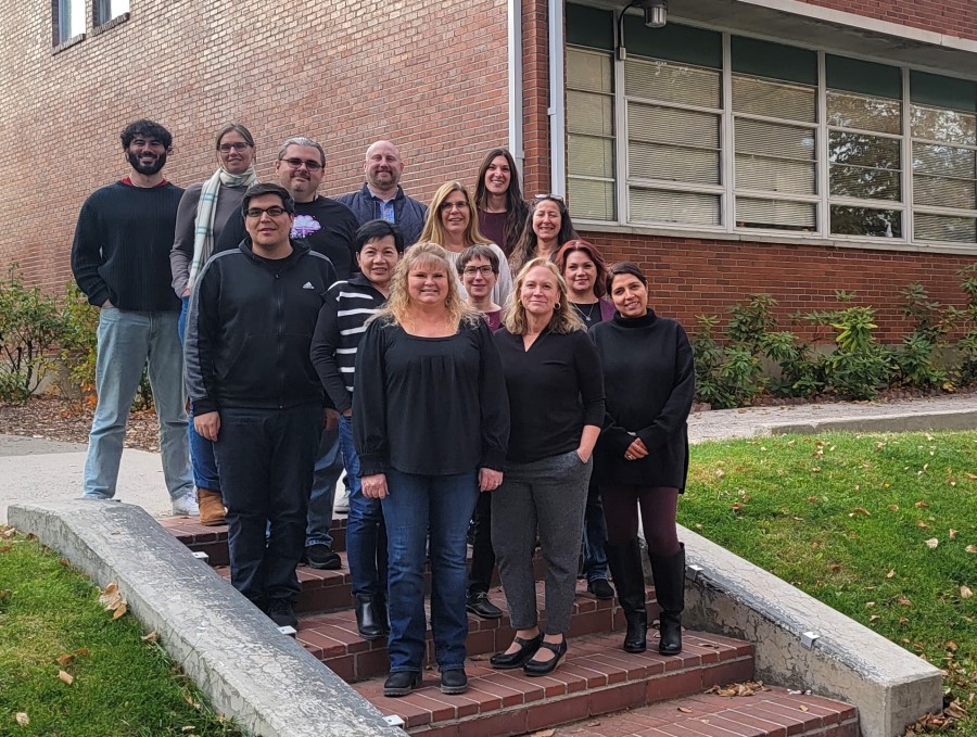 A group of people pose for a photo on a sidewalk stair case outside Ross Hall on the University of Nevada, Reno campus.