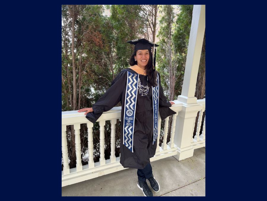 Xochitl Salinas standing in front of a railing in her cap and gown.