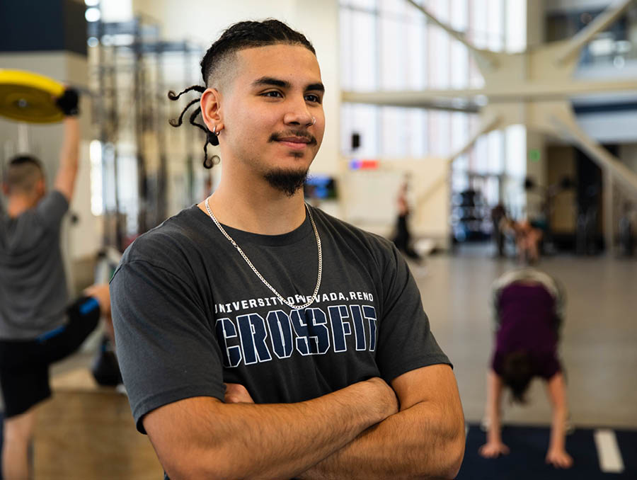 Gym student worker Angel Barboza with arms crossed while looking into the distance