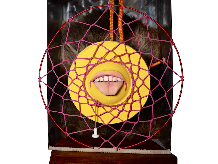 A piece of art that depicts a human mouth surrounded by a yellow circle and a dreamcatcher like structure of sting.