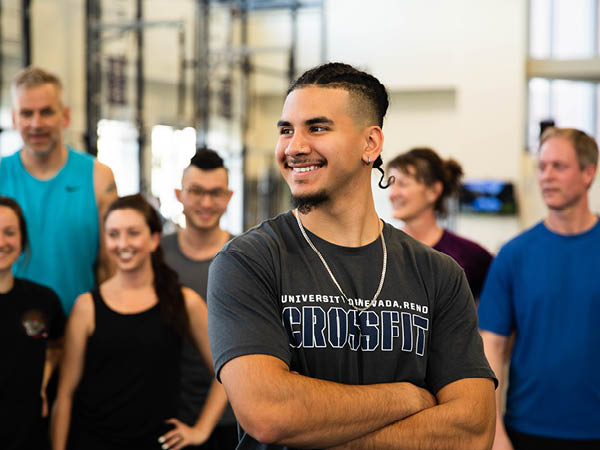 Angel Barboza standing in front of his students smiling with his arms crossed.