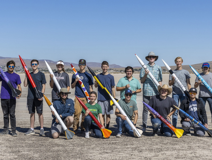 Members of the Aerospace Club stand in the desert holding the rockets they built