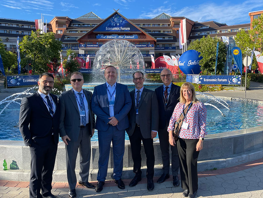 Five faculty stand in front of a fountain outside of the International Economic Forum.