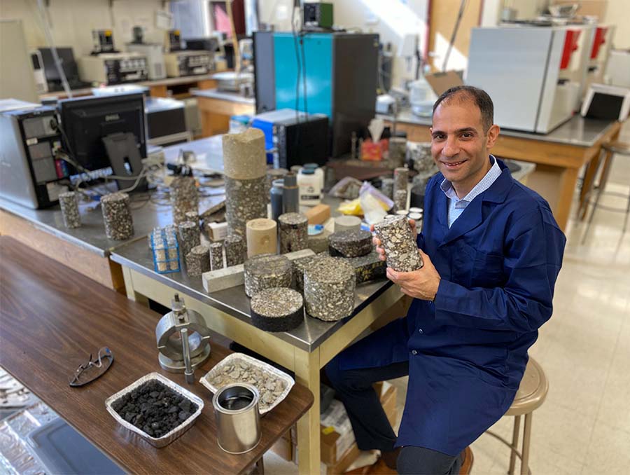 Elie Hajj sitting in lab holding a pavement core sample.