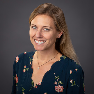 Kathy Hanselman stand in a floral shirt smiling at the camera