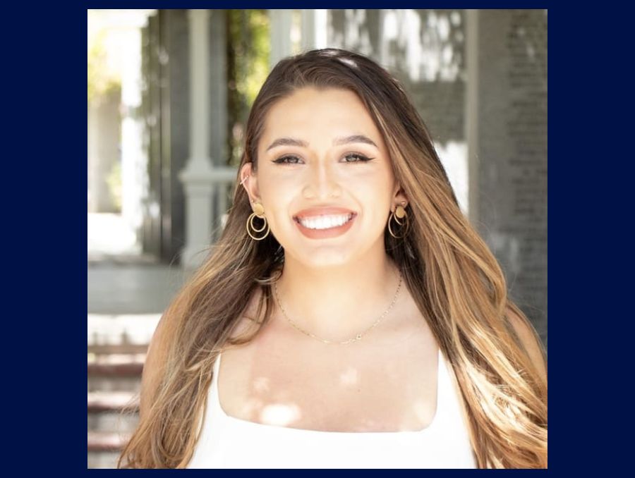 Maggie Otero smiling at the camera in a white shirt