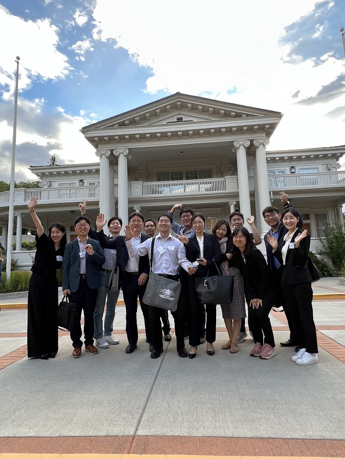 A large group makes silly poses in front of the Governor's mansion.