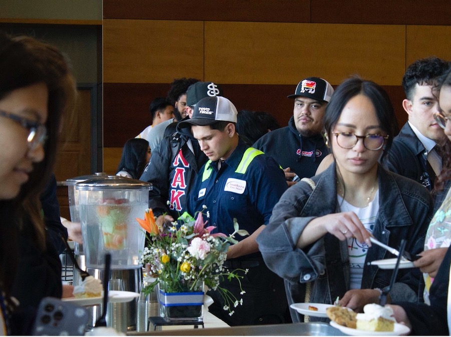 A group of students getting food from a buffet at an event. 