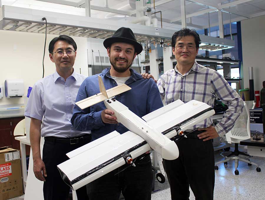 Three people standing in a lab: Assistant Professor Jihwan Yoon; student Jeremy La Porte, holding a model plane; and Associate Professor Jeongwon Park.