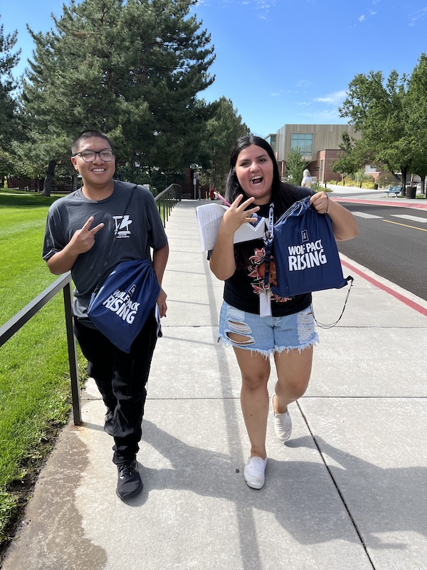 Two students smile while walking on campus