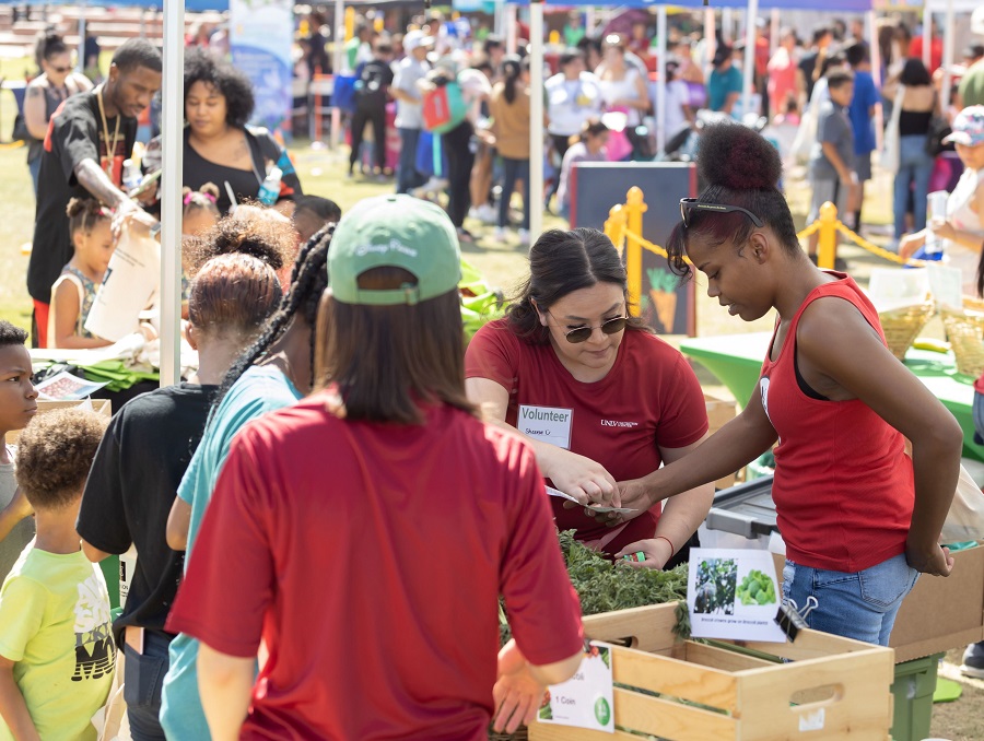 A volunteer at the festival talking to youth at the farmers market booth.