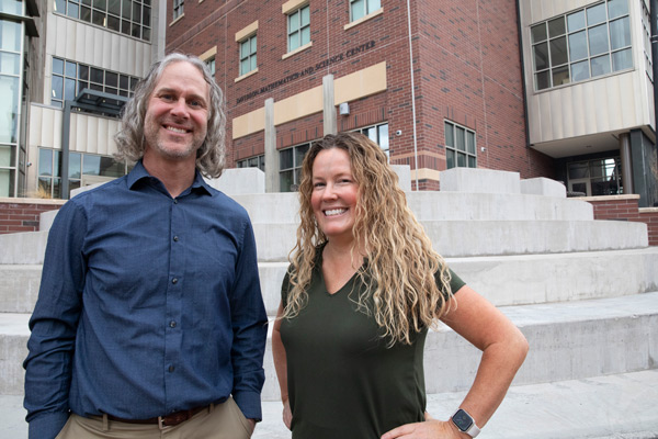 Jennifer Hollander and Jeff Baguley smile in front of the Davidson Mathematics and Science Center.