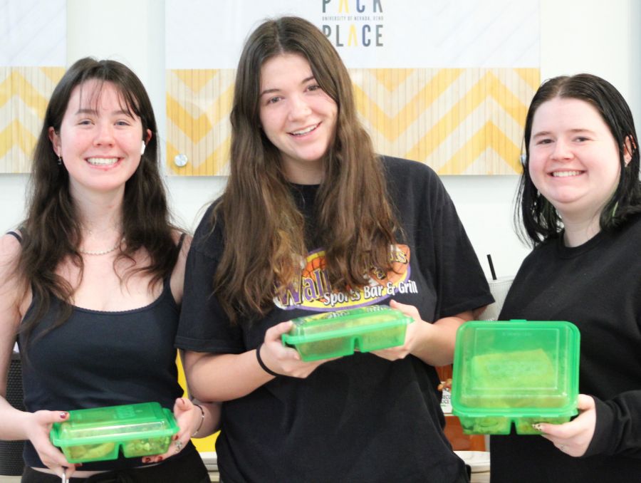 Three students posing and holding up green reusable containers
