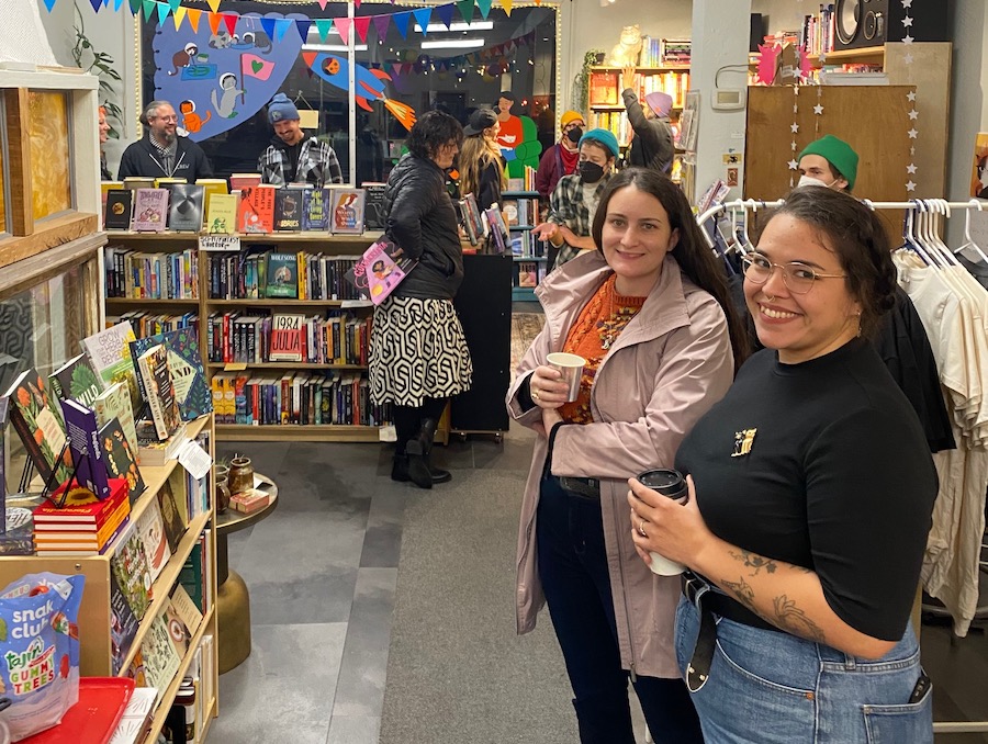 Two people pose for the camera in a bookstore.