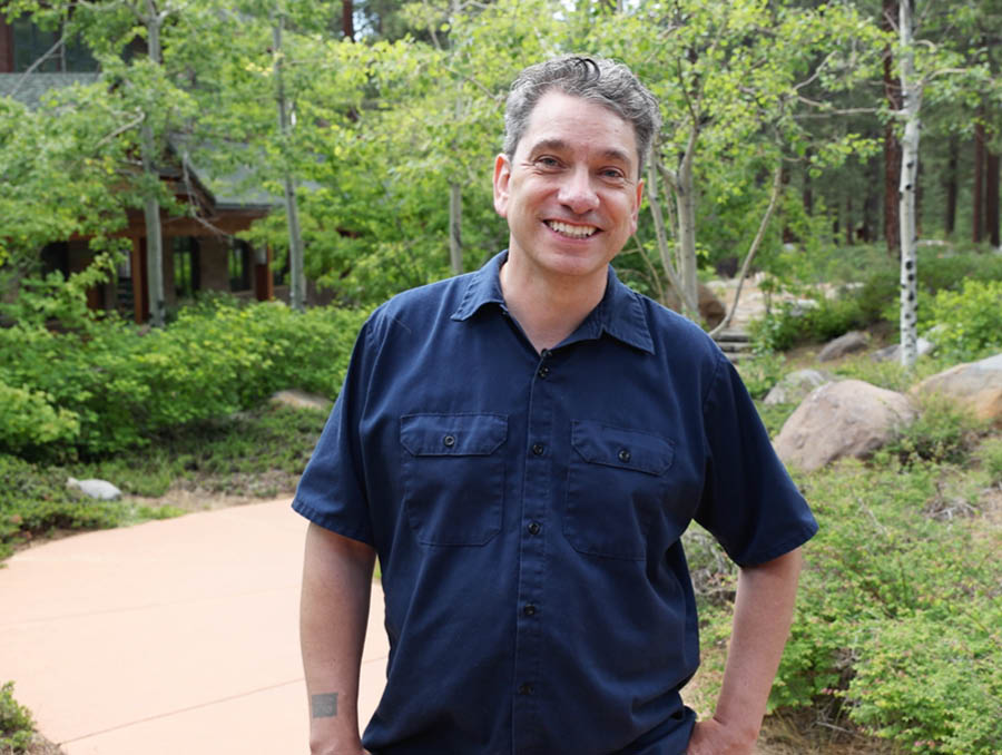 Chirs Lanier stands on a path surrounded by aspens at the University of Nevada, Reno at Lake Tahoe