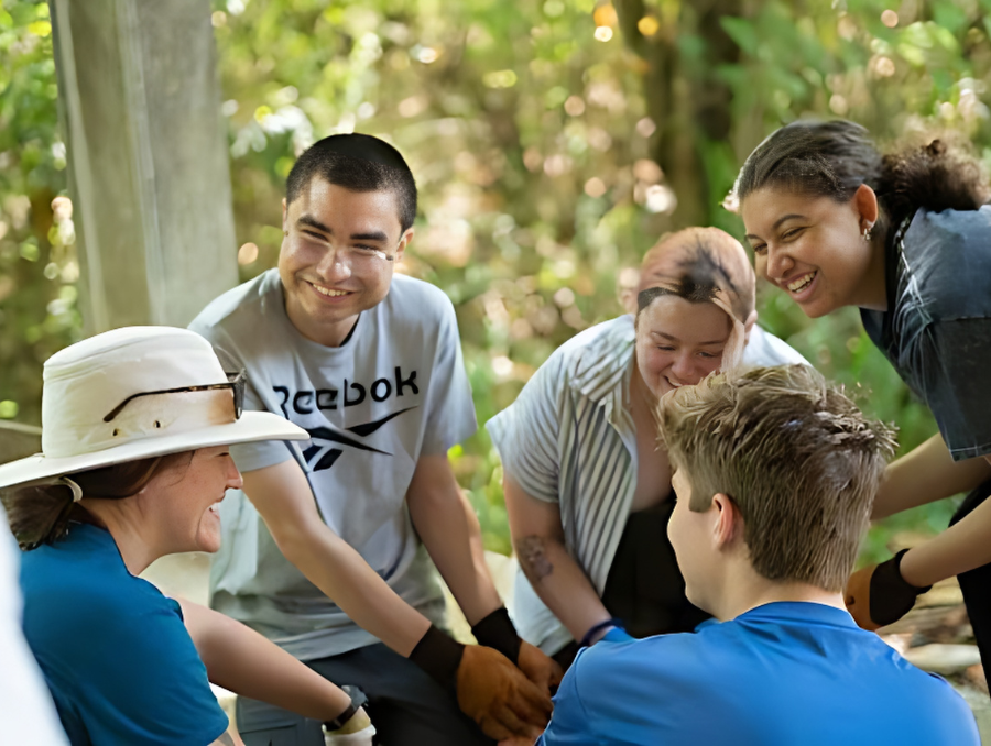 Jorge Esparza sits in a group of four other individuals, all smiling while working together.