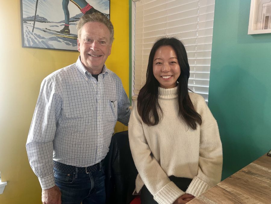 A man stands next to a woman in a coffee shop, smiling.