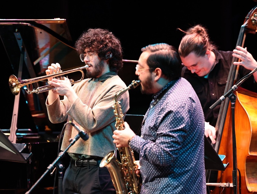 Three musicians playing their instruments on stage.