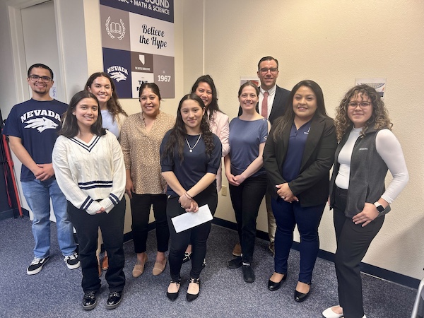 Karla Hernandez stands with a group of young people in a classroom.