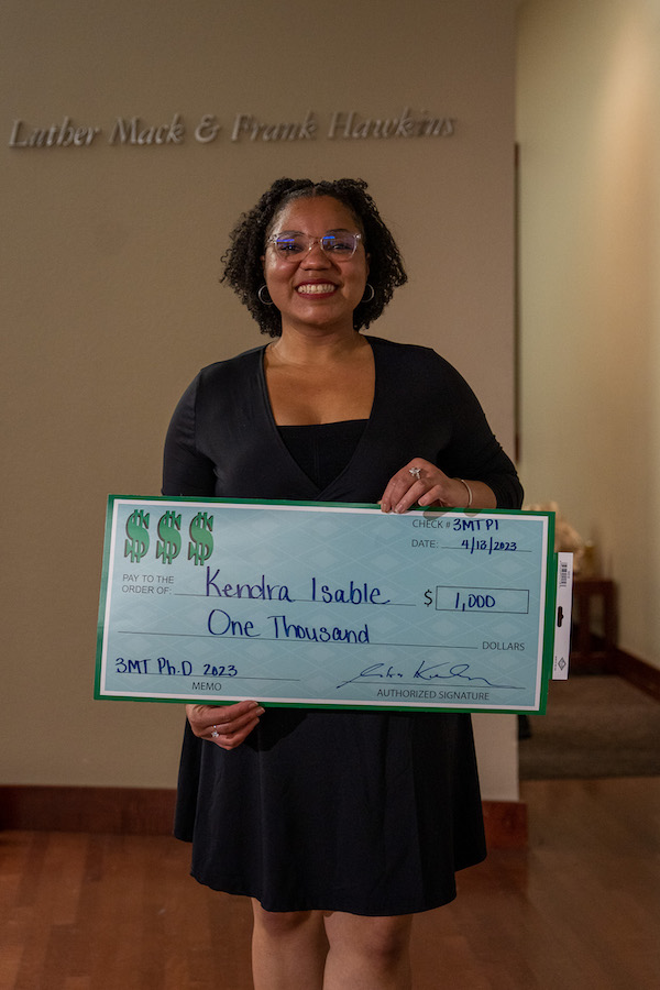 Kendra holds a giant check.