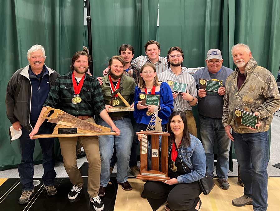 A group of people holding plaques and trophies smiles for a photo.