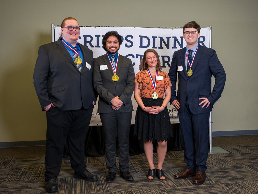 Four student scholarship recipients, each with a gold medal around their necks.