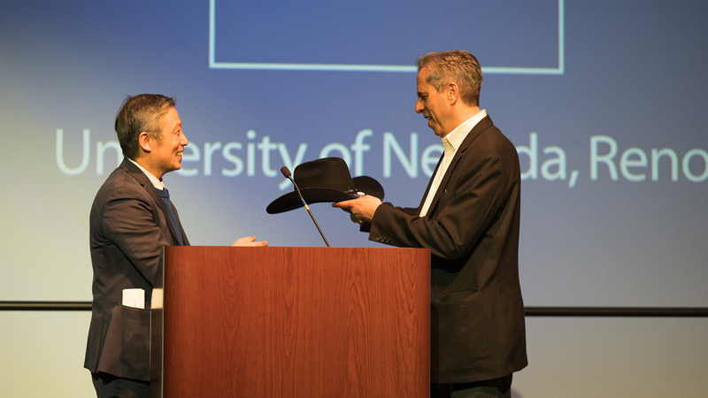 Dean Yun presenting Steven Waldman with a hat on stage