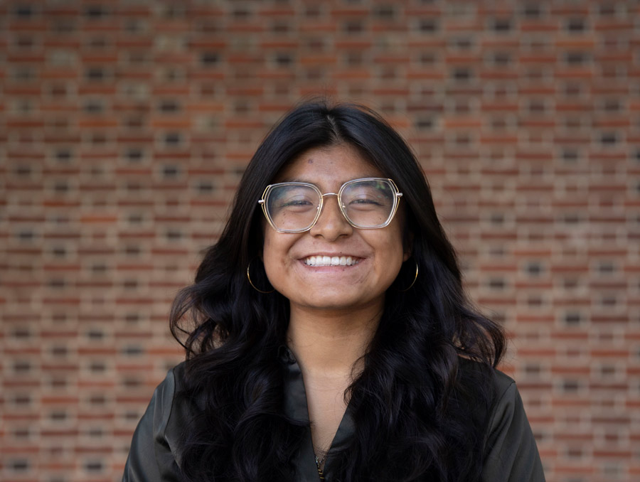 A portrait of Yajahira Dircio smiling in front of a brick wall.