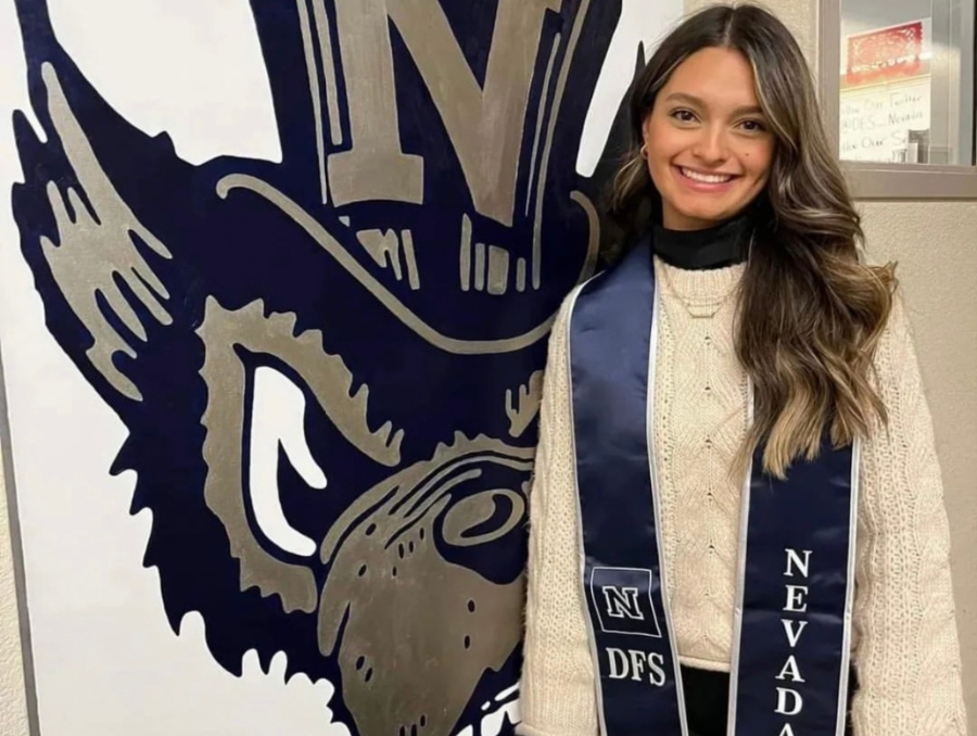 Jada DeLeon wearing her graduation stole in front of a classic Wolf Pack mascot graphic