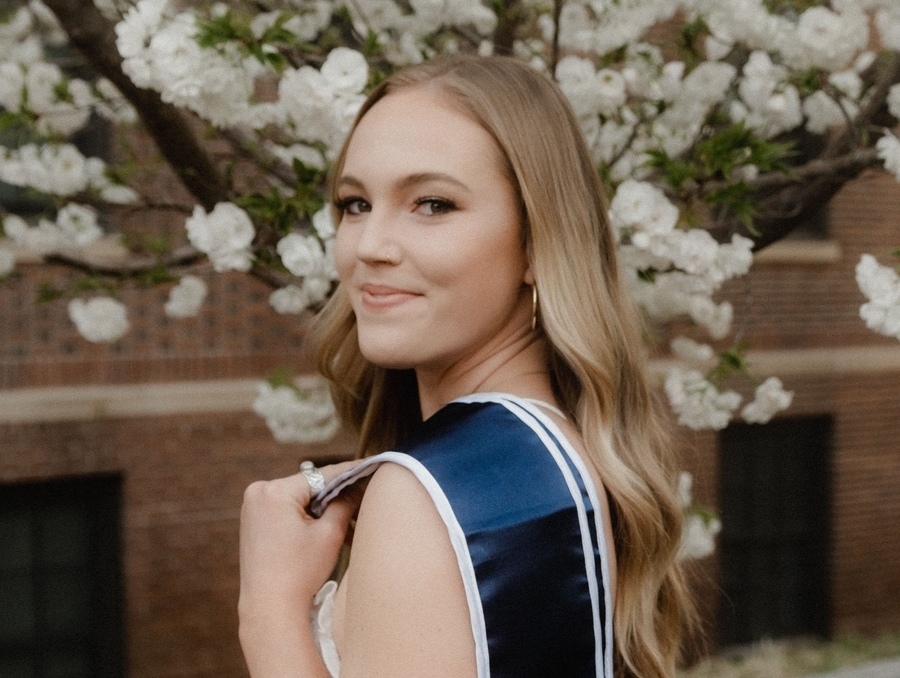 Madelyn Montgomery smiling in front of a blooming tree.