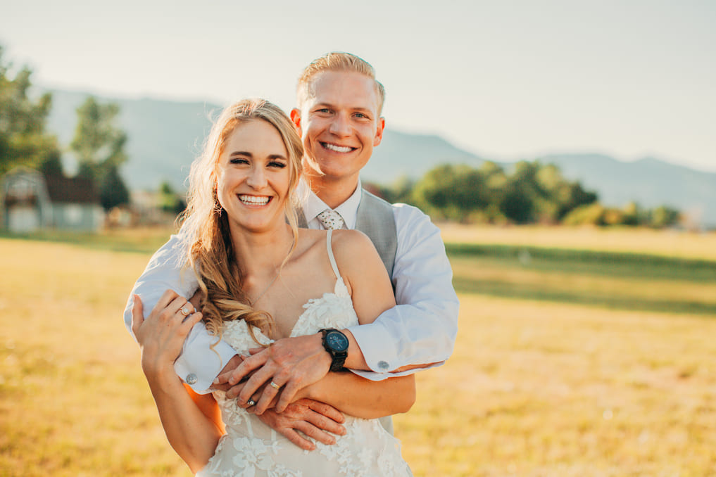 Spencer and his wife, Kat, smiling outside on their wedding day.