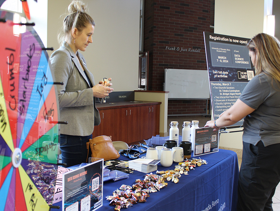 Two people preparing and setting up for a tabling event.