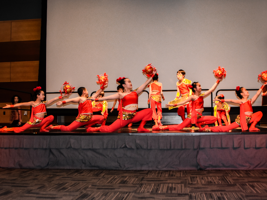 A group of performers dressed in red dance on a stage.
